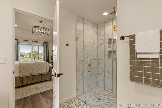ensuite bathroom with a stall shower, a chandelier, recessed lighting, wood finished floors, and baseboards
