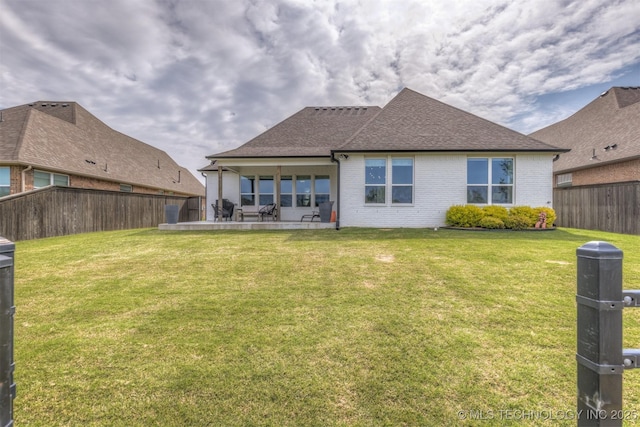 rear view of property featuring brick siding, a shingled roof, and a patio