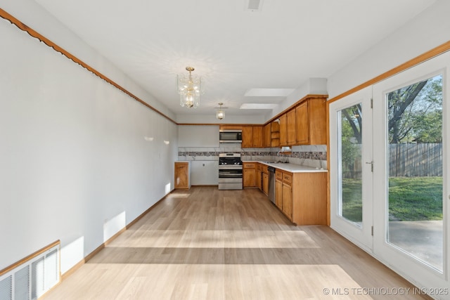 13973 S Hickory St, Glenpool, OK 74033 - kitchen with light wood-style flooring, visible vents, a notable chandelier, brown cabinetry, and appliances with stainless steel finishes