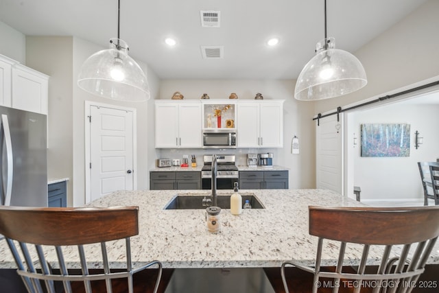 13010 E 125th Pl N, Collinsville, OK 74021 - kitchen with appliances with stainless steel finishes, a barn door, a breakfast bar area, white cabinets, and recessed lighting