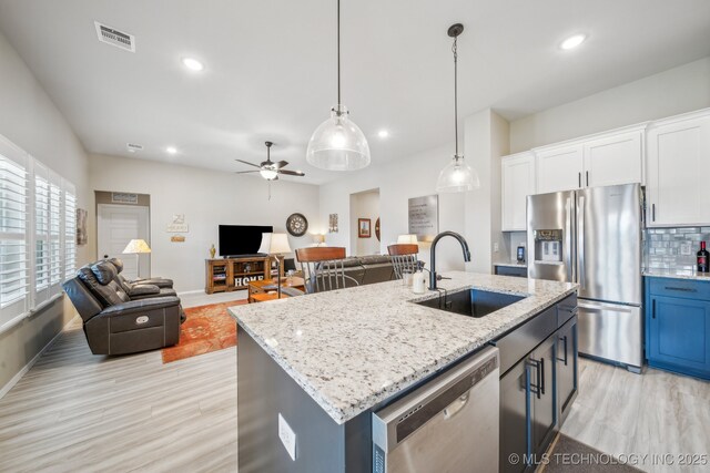 13010 E 125th Pl N, Collinsville, OK 74021 - kitchen featuring appliances with stainless steel finishes, light wood finished floors, white cabinetry, open floor plan, and recessed lighting