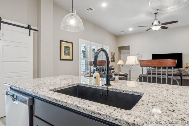 13010 E 125th Pl N, Collinsville, OK 74021 - kitchen featuring stainless steel dishwasher, open floor plan, a barn door, ceiling fan, and light stone countertops
