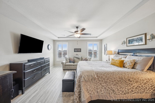 13010 E 125th Pl N, Collinsville, OK 74021 - bedroom with light wood-style floors, a tray ceiling, and ceiling fan