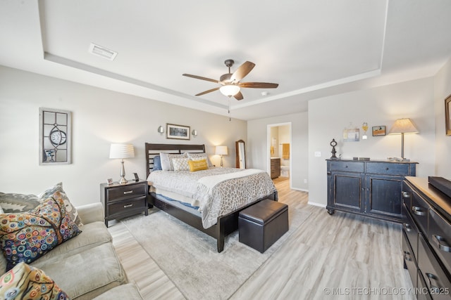 13010 E 125th Pl N, Collinsville, OK 74021 - bedroom featuring a tray ceiling, light wood-style flooring, ceiling fan, and ensuite bathroom