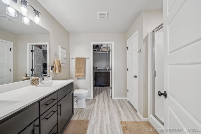 13010 E 125th Pl N, Collinsville, OK 74021 - bathroom featuring double vanity, wood finished floors, a shower stall, and a spacious closet