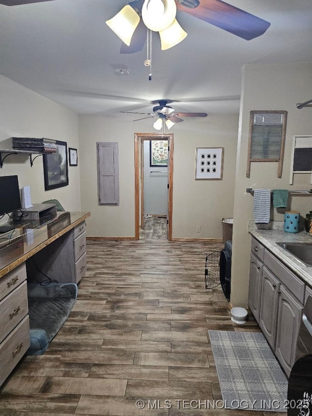 office space featuring baseboards, a ceiling fan, dark wood-type flooring, and a sink