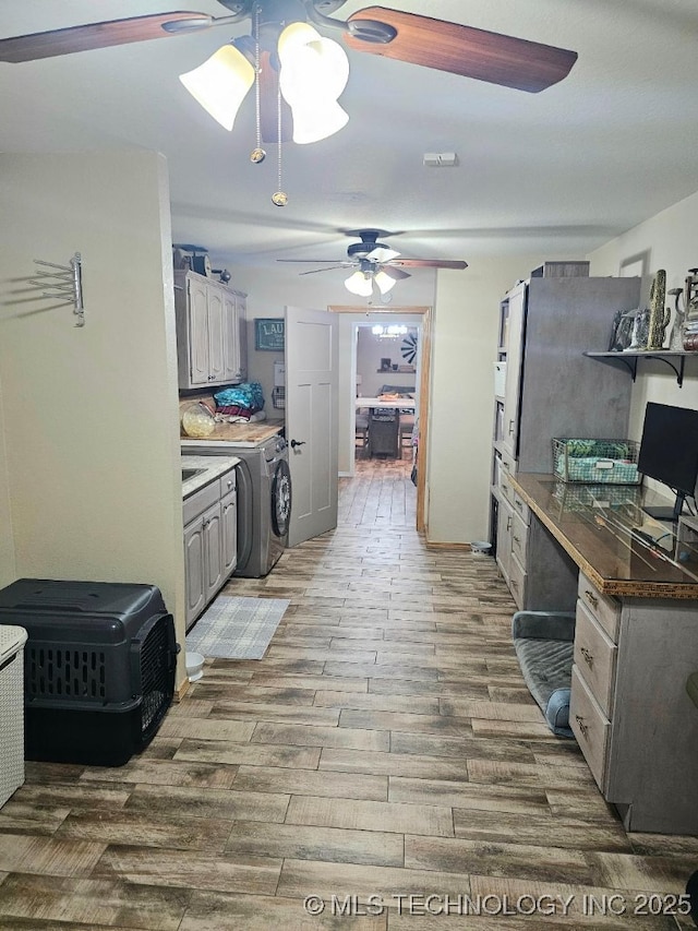 kitchen featuring wood finished floors, a ceiling fan, gray cabinets, and washer and clothes dryer