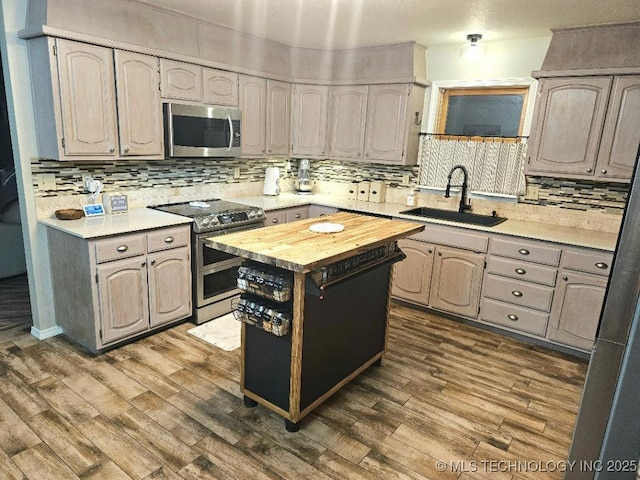 kitchen with wood counters, decorative backsplash, appliances with stainless steel finishes, and a sink
