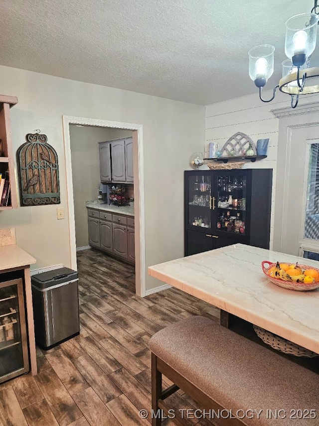 dining room featuring dark wood finished floors, baseboards, a textured ceiling, and wine cooler