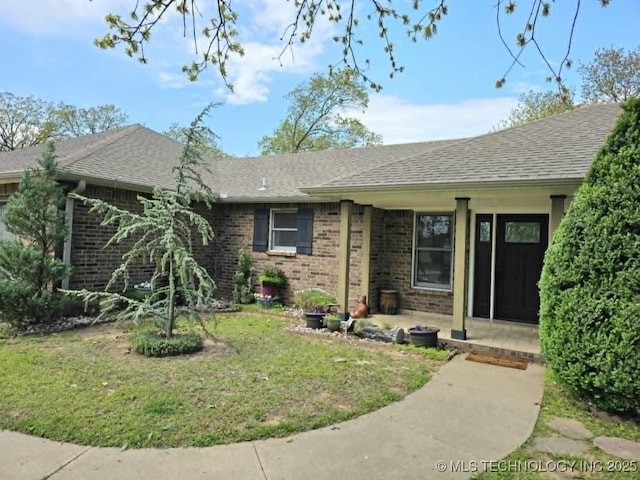 single story home with brick siding, a shingled roof, and a front lawn