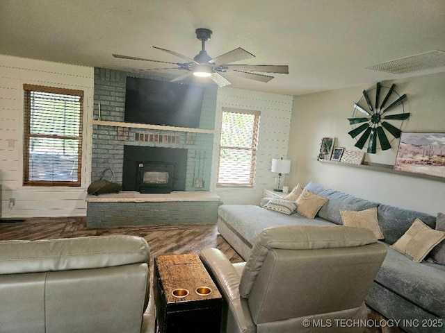 living room featuring a ceiling fan, wood finished floors, and a fireplace