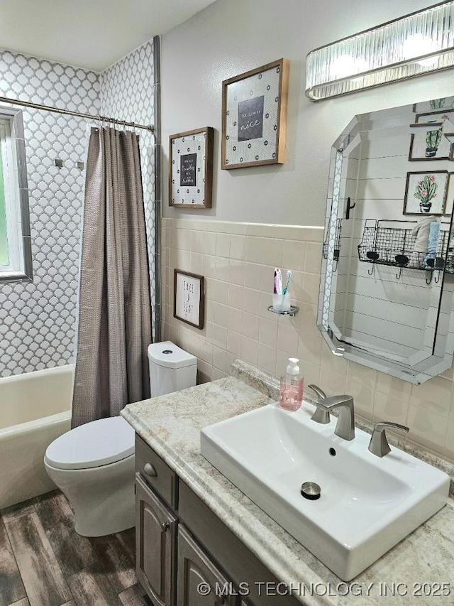full bath featuring wood finished floors, toilet, vanity, tile walls, and shower / tub combo