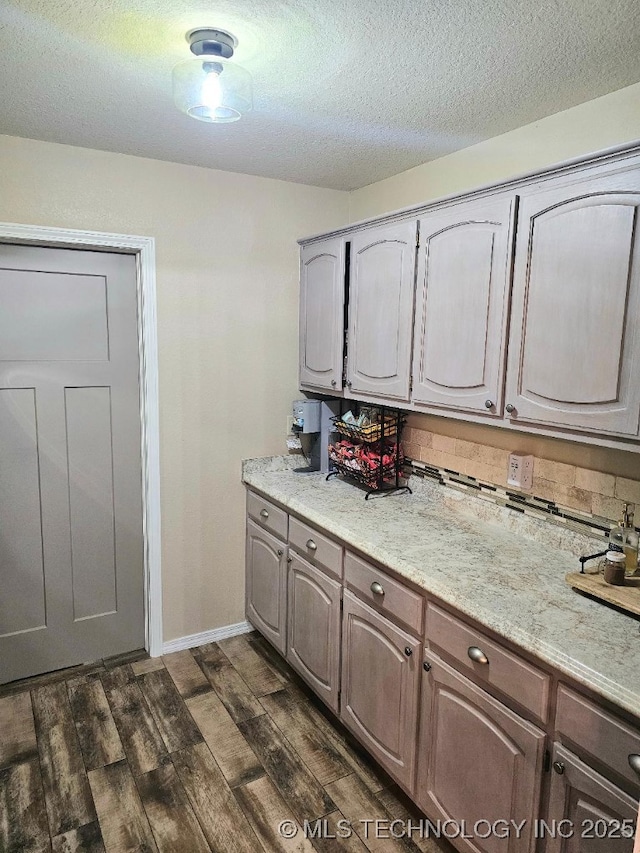 clothes washing area with baseboards, dark wood-style floors, and a textured ceiling