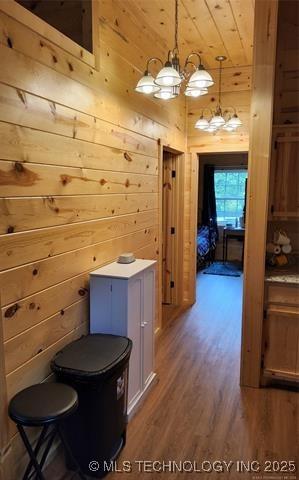 bathroom featuring a chandelier, wooden ceiling, wood finished floors, and wooden walls