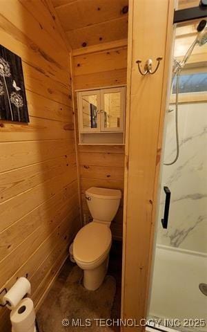 bathroom featuring wooden walls, toilet, and a walk in shower
