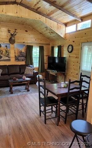 dining area featuring vaulted ceiling with beams, wooden walls, wood finished floors, and wood ceiling