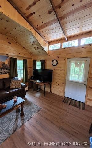 living area featuring wood walls, wood finished floors, lofted ceiling with beams, and wooden ceiling