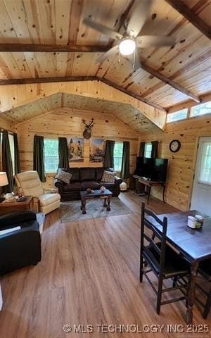 living area with wood ceiling, a wealth of natural light, wooden walls, and vaulted ceiling with beams