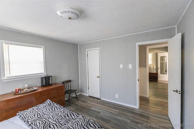 bedroom featuring dark wood finished floors, baseboards, ornamental molding, and a textured ceiling
