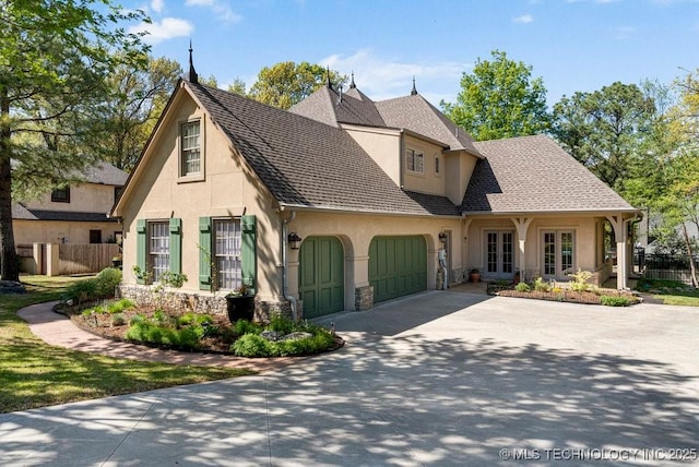view of front of house featuring driveway, a garage, stucco siding, and fence