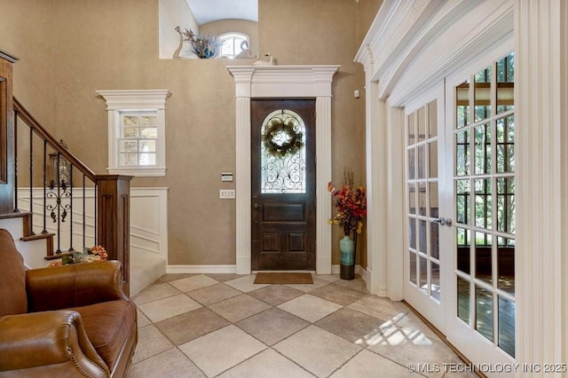 foyer entrance featuring a towering ceiling, a healthy amount of sunlight, and stairs