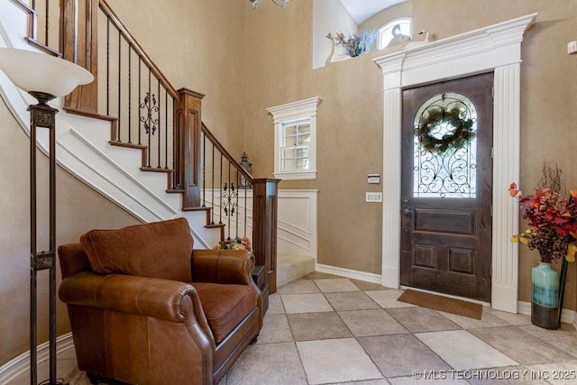 entrance foyer featuring a towering ceiling, baseboards, and stairs
