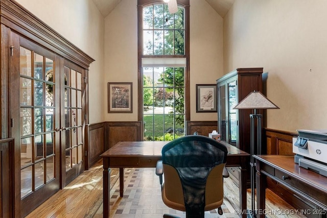 office area with a decorative wall, high vaulted ceiling, wainscoting, and french doors