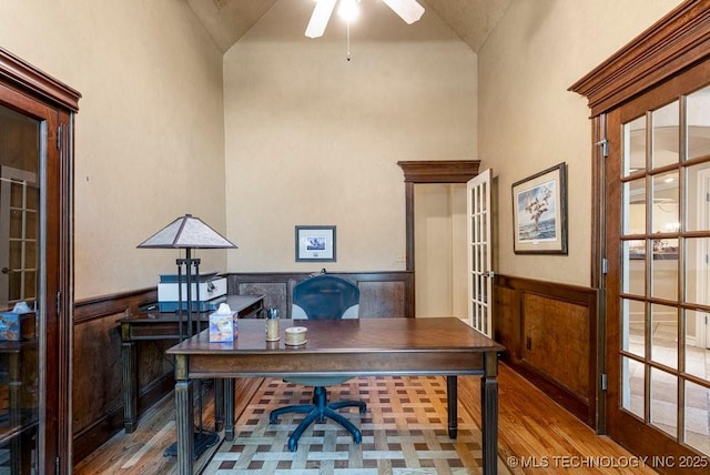 office with ceiling fan, high vaulted ceiling, wood finished floors, wainscoting, and french doors