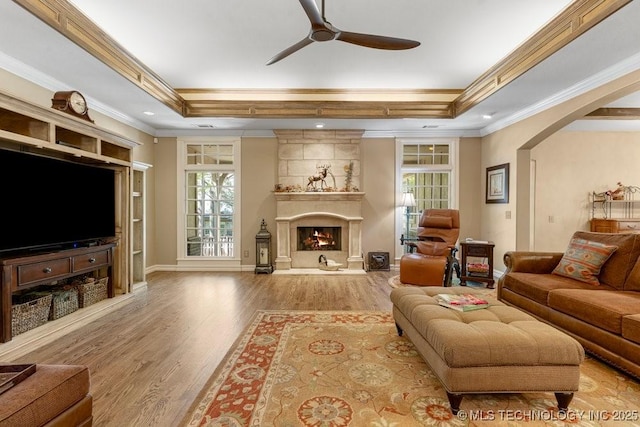 living room with wood finished floors, a ceiling fan, crown molding, and a tray ceiling