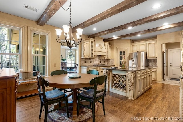 dining space with visible vents, beam ceiling, an inviting chandelier, recessed lighting, and wood finished floors