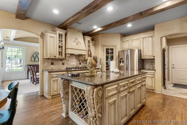 kitchen with stainless steel appliances, wall chimney exhaust hood, and cream cabinetry