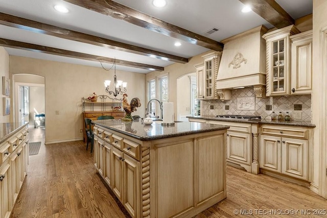 kitchen with visible vents, arched walkways, cream cabinets, and a sink