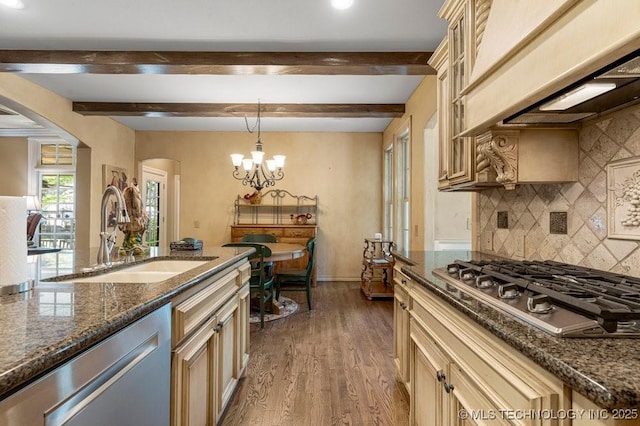 kitchen featuring tasteful backsplash, a sink, appliances with stainless steel finishes, arched walkways, and cream cabinets