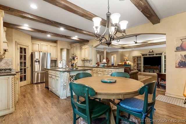 dining space with beamed ceiling, light wood finished floors, recessed lighting, and ceiling fan with notable chandelier