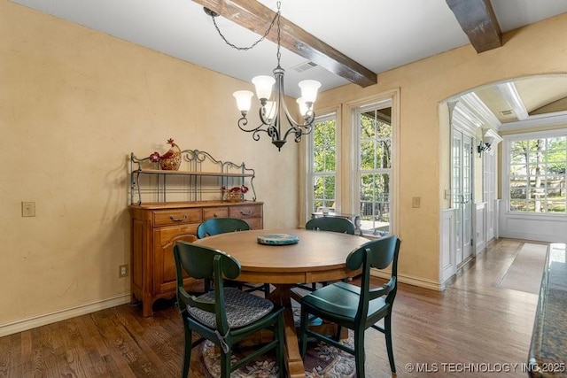 dining space featuring wood finished floors, arched walkways, beamed ceiling, baseboards, and visible vents
