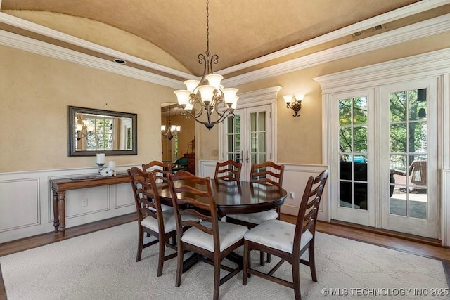 dining area with a chandelier, crown molding, light wood finished floors, and vaulted ceiling