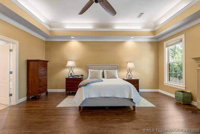 bedroom with baseboards, visible vents, wood finished floors, and a tray ceiling