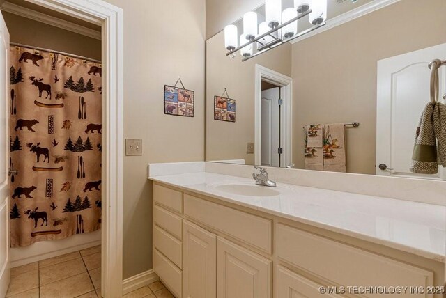 bathroom featuring baseboards, tile patterned flooring, crown molding, and vanity