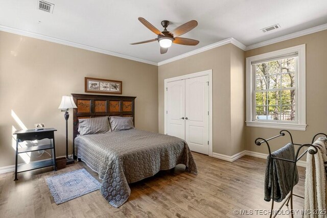 bedroom with baseboards, visible vents, and wood finished floors