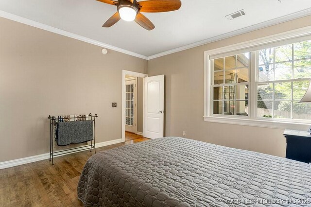 bedroom with baseboards, visible vents, wood finished floors, and ornamental molding