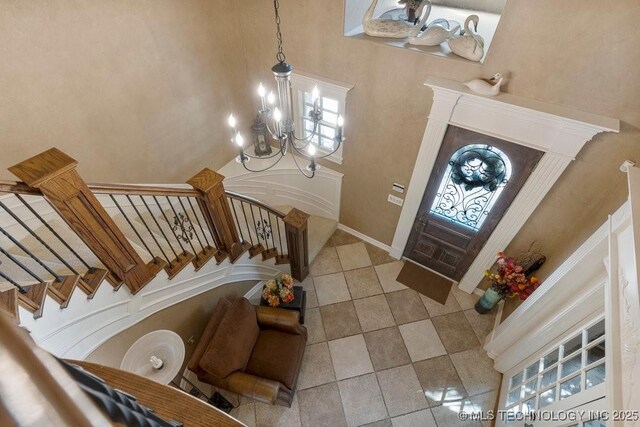 tiled entrance foyer with a towering ceiling, stairway, a wealth of natural light, and a chandelier