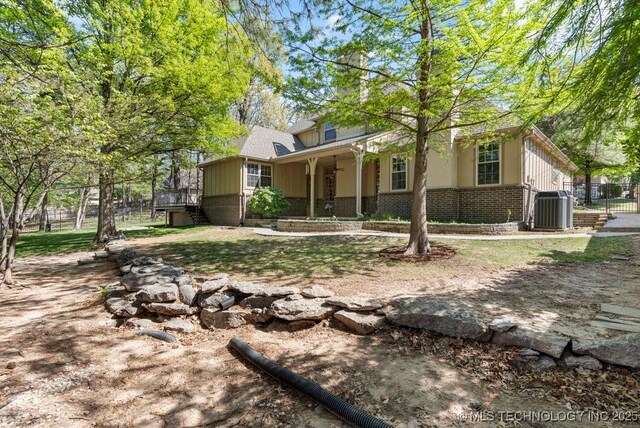 view of front of home featuring fence, central AC, and brick siding