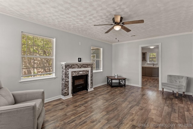living room featuring ornamental molding, wood finished floors, a fireplace, and ceiling fan