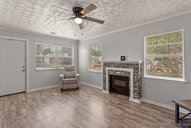 living area featuring visible vents, a ceiling fan, wood finished floors, and a fireplace