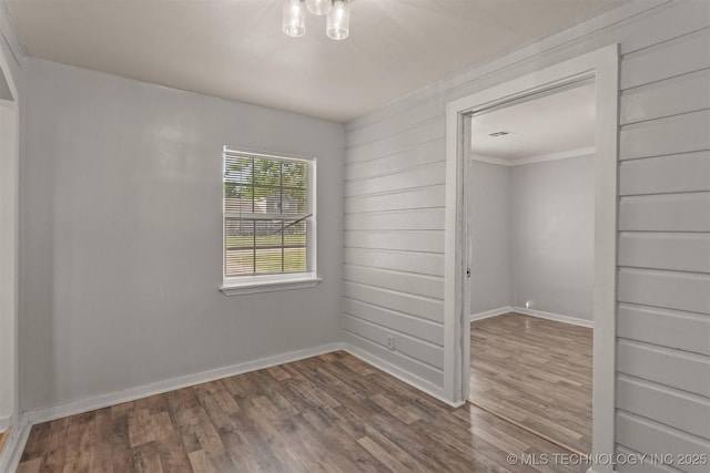 spare room featuring baseboards, ornamental molding, and wood finished floors