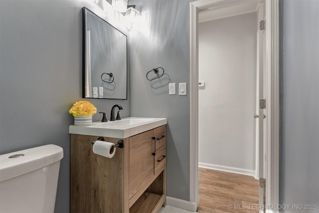bathroom featuring toilet, vanity, wood finished floors, and baseboards