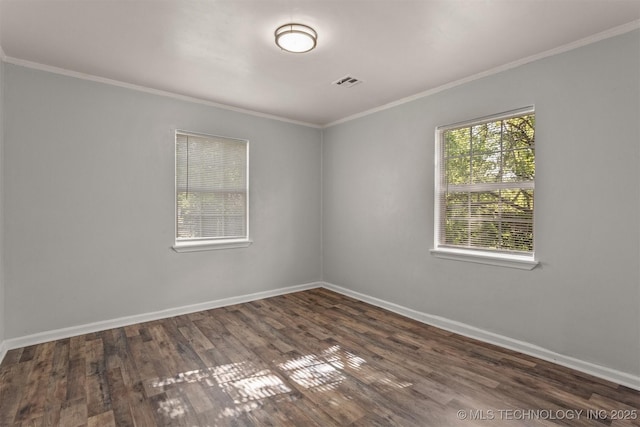 empty room with baseboards, wood finished floors, visible vents, and ornamental molding