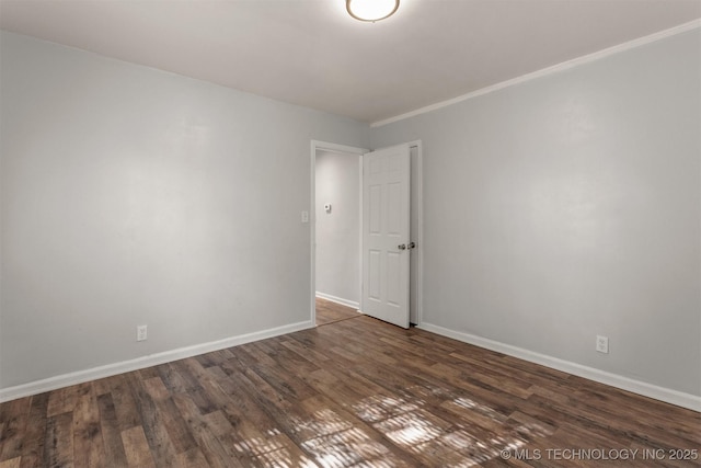 spare room with baseboards, wood finished floors, and crown molding
