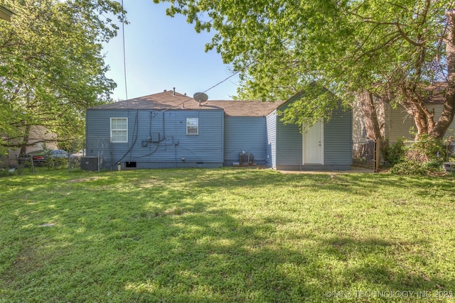 rear view of house with roof with shingles, fence, and a yard