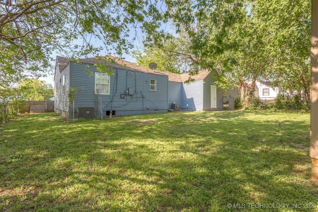 rear view of house with a lawn and fence